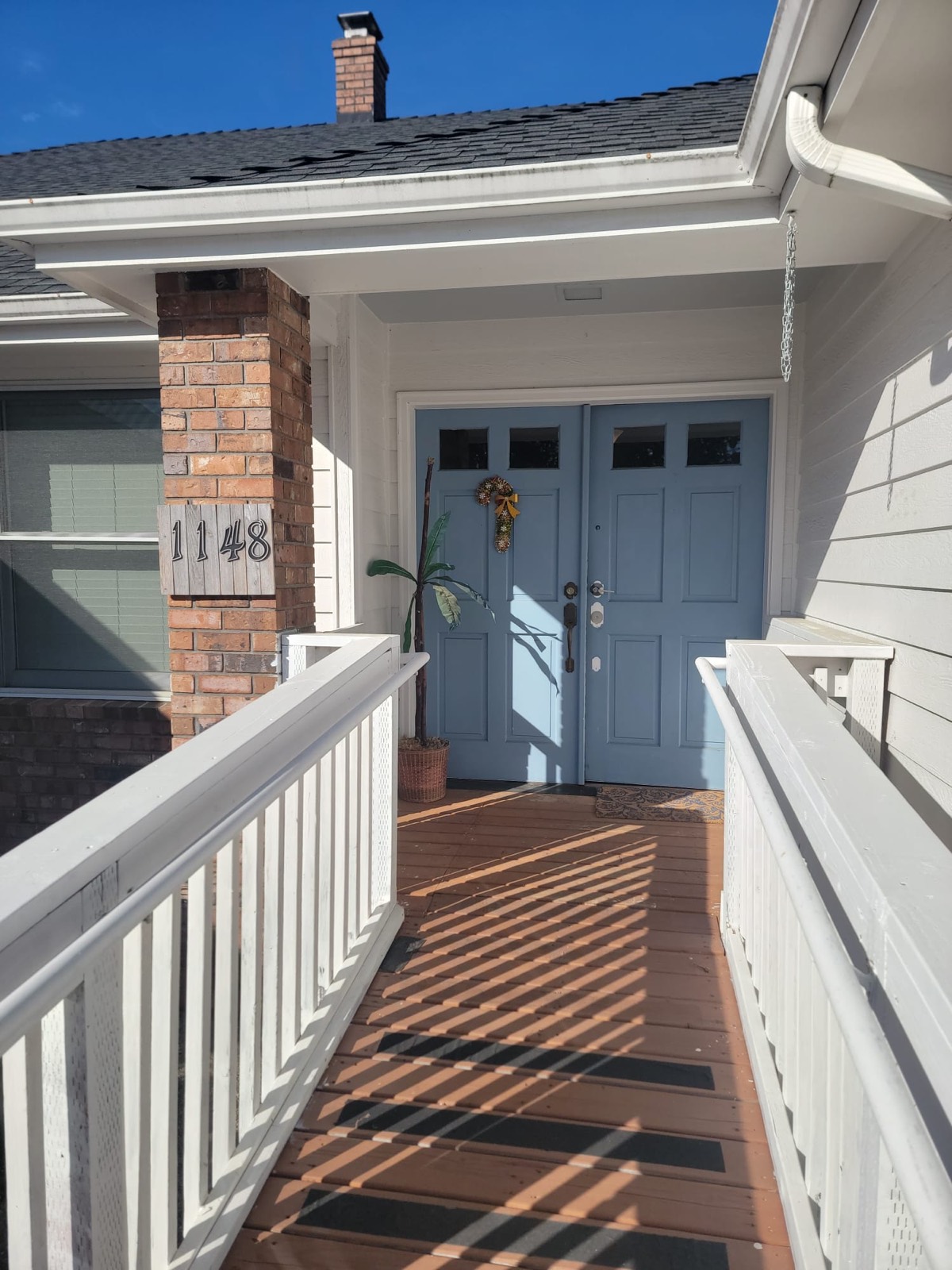 The railed ramp leading up to the home's blue double front doors.